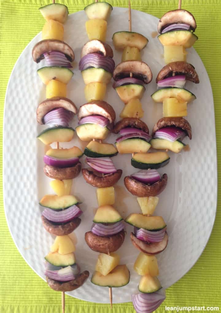 several marinated vegetable skewers on white oval plate