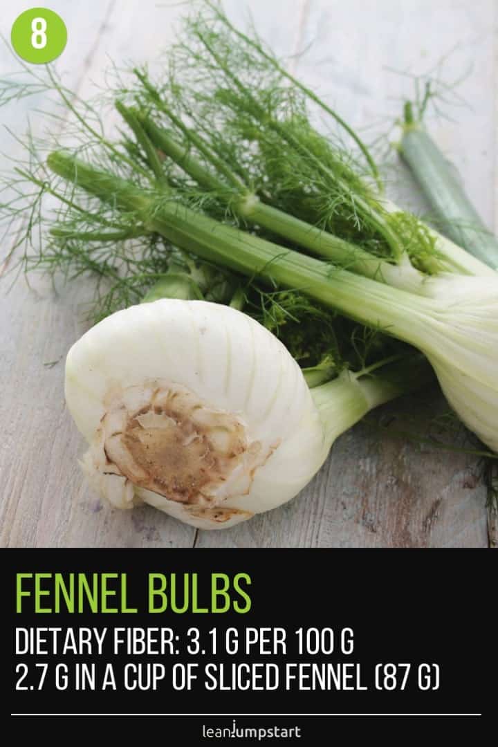 two fennel bulbs with fronds on white wood