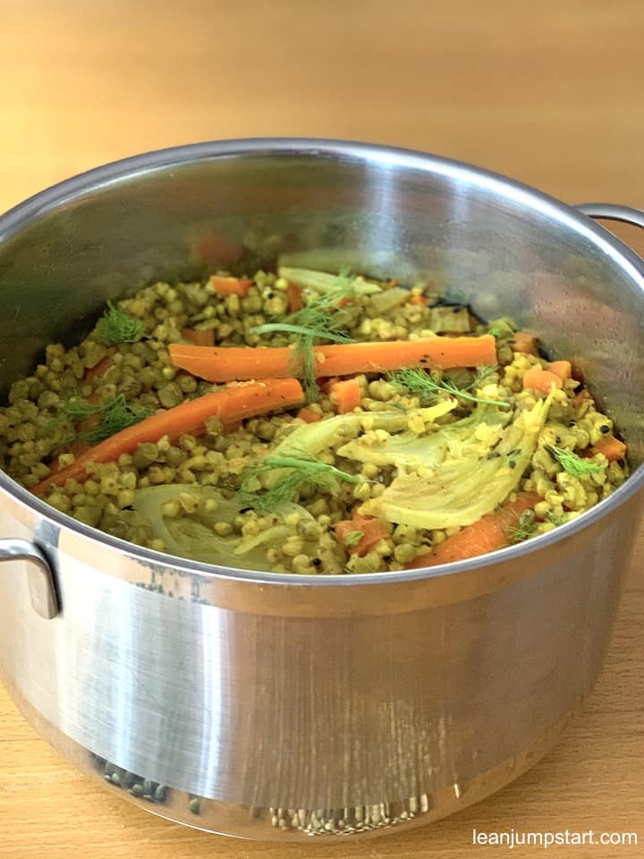 a pot with cooked mung beans and buckwheat topped with carrots and fennel