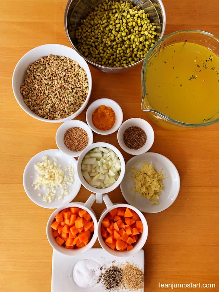 all kitchari ingredients top view showing mung beans, buckwheat, vegetable broth, onions, carrots, garlic, ginger and other spices 