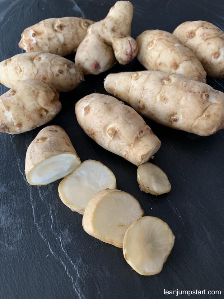 a couple of raw sunchokes on a black chalkboard background