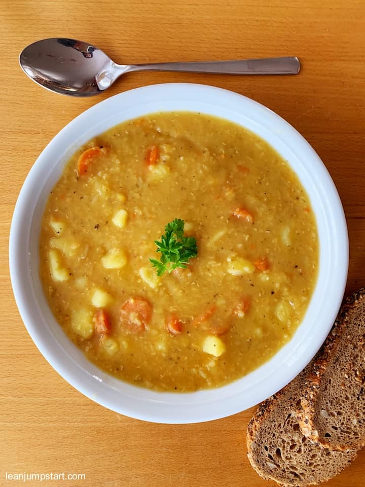 red lentil soup in a plate with whole grain bread