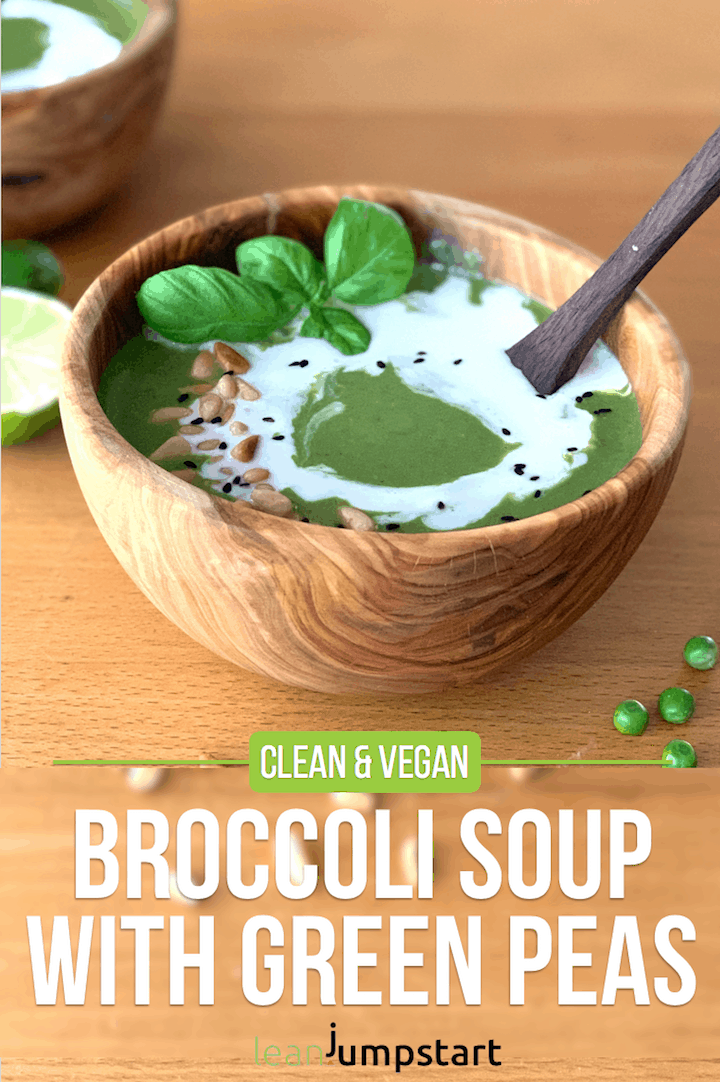 Top view of cream of broccoli soup in a wooden bowl topped with coconut milk, sprinkled by roasted pine nuts and black cumin, garnished with some basil leaves