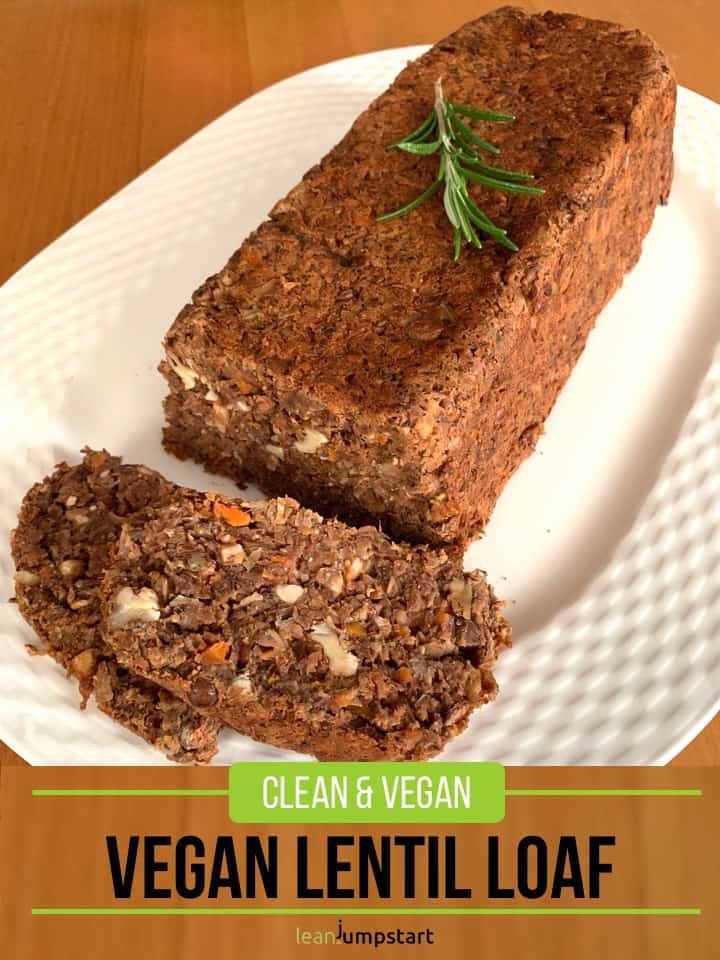 whole vegan lentil loaf on a large oval plate with slices cut and a rosemary stalk